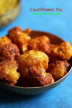 some fried food in a metal bowl on a blue tablecloth with a yellow flower