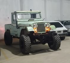 an old green jeep is parked in a garage