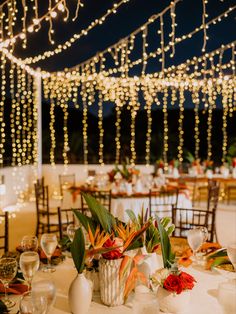 the tables are set with white linens and decorated with flowers, greenery and lights