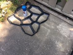 a glass tray sitting on the ground next to a wooden fence with a bottle in it