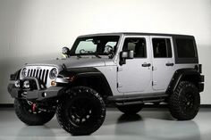 a silver jeep parked in a garage next to a white wall