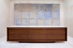 a wooden cabinet sitting in front of a wall with blue tiles on the top and bottom