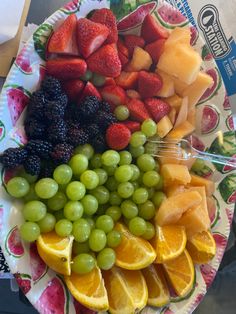 a plate with grapes, oranges, and strawberries on it