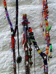 there are many necklaces hanging up on the wall with beads and bells attached to them