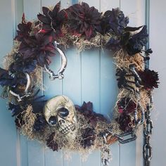 a wreath with skulls and flowers hanging on the front door to decorate it for halloween