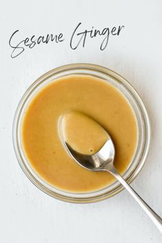 a spoon in a glass bowl filled with peanut butter sauce and the words sesame ginger above it