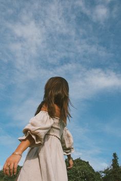 a girl in a white dress is flying a kite