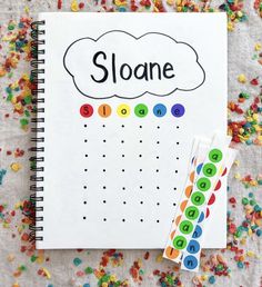 a spiral notebook with the word sloane written on it next to colorful sprinkles