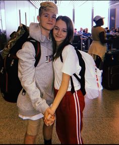 two people standing next to each other in an airport