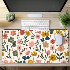 a computer mouse pad with flowers on it next to a keyboard and a potted plant