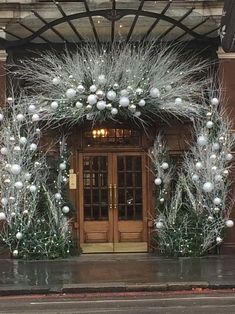 an entrance to a building decorated with silver and white christmas decorations on the front door