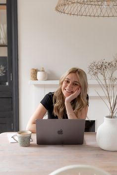 a woman sitting at a table with her laptop