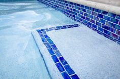 an empty swimming pool with blue tiles on the side and water in the back ground