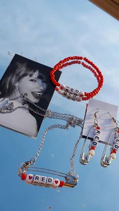 the necklaces are hanging from the clothesline and have pictures on them with name tags attached to them