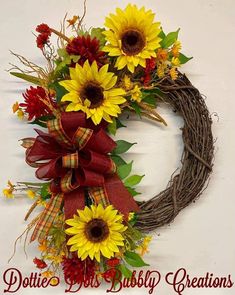 a wreath with sunflowers and red ribbon on it that says dottie's gifts ruby creations