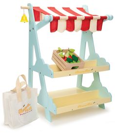 a wooden toy stand with fruits and vegetables on it next to a white shopping bag