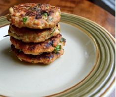 three crab cakes stacked on top of each other on a white plate with green trim