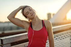 a young woman listening to music on her headphones while sitting on a bench in the sun