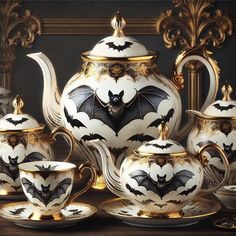 a tea set with bats painted on it and gold trimmings around the edges