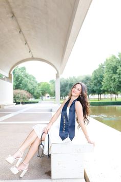 a woman sitting on top of a white box wearing a blue tie and high heels