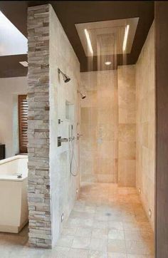 a walk in shower sitting next to a white bath tub under a skylight on top of a tiled floor