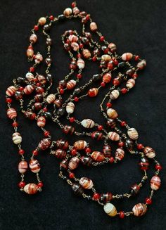 On offer here are two stunning Art Deco necklaces that I would date from around the 1930's There are two strands on offer as I did not really want to separate them as they compliment each other so well.  The long strand (110 cm) is striped agate beads, highly polished and beautifully crafted in a wide range of colours but essentially terracotta through to white with bands of red, brown and gold throughout.  Between each wired bead is a wired carnelian stone. No clasp these are made for layering The slightly 'shorter strand' is 96 cm long and the agate stones are predominately black but with terracotta highlights and flashes of other colours including gold.  In between each wired bead is a small black glass bead. The stones are beautiful and each one is different and the necklaces look wond Vintage Round Bead Necklaces Collectible, Vintage Polished Beads Necklace, Vintage Single Strand Round Necklace, Vintage Polished Beads Round Necklace, Vintage Round Polished Beads Necklace, Vintage Round Necklaces With Polished Beads, Antique Single Strand Necklace Gift, Antique Jewelry With Round Beads For Vintage Collection, Antique Single Strand Necklace As Gift