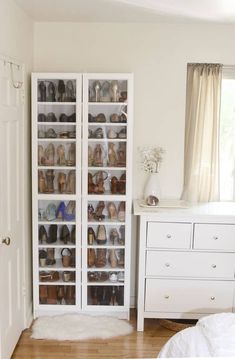 a white closet filled with lots of shoes next to a dresser and bed in a room