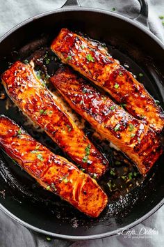 salmon fillets in a skillet ready to be cooked with sauce and seasonings