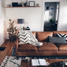 a living room with a couch, coffee table and christmas tree in the corner on the wall