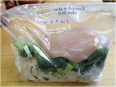 chicken breast and broccoli wrapped in plastic on top of a wooden countertop