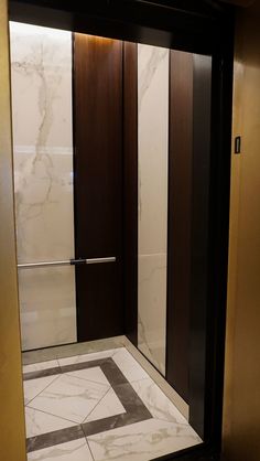 an elevator with marble floors and brown doors