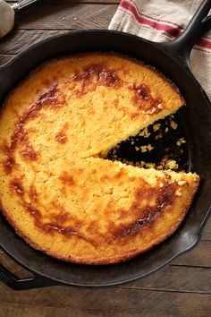 a skillet with a cake in it on a wooden table next to utensils