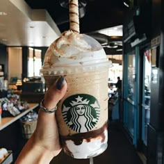 a hand holding up a starbucks drink in a restaurant