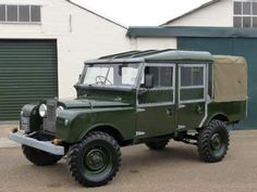 an army green truck parked in front of a building