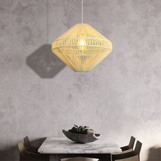 a dining room table with a bowl of fruit on it and a hanging light fixture