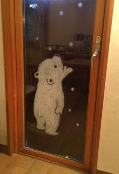 a teddy bear drawn on the glass door to a room with wooden floors and walls