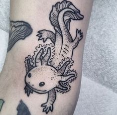 a black and white photo of a lizard tattoo on the left leg, with its tail curled up