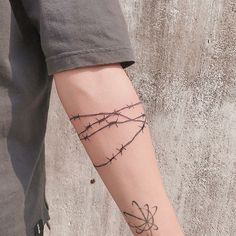 a person with a tattoo on their arm that has barbed wire attached to the wrist