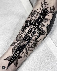 a black and white tattoo on the arm with roses, leaves and scissors in it