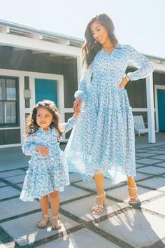 mother and daughter holding hands in front of a building