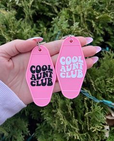 two pink tags with the words cool run club on them are held by a woman's hand