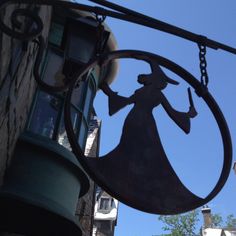 a sign hanging from the side of a building with a woman holding a wand in it's hand