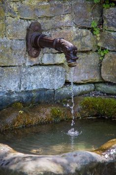 a faucet with water coming out of it in front of a stone wall