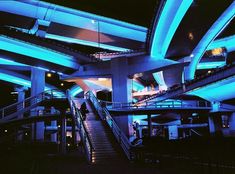 an escalator in a building with blue lights on it and people walking up the stairs