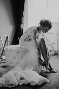 a woman kneeling down on the floor in front of a chair with her wedding dress