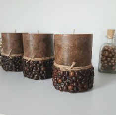 three candles are wrapped in twine and surrounded by coffee beans