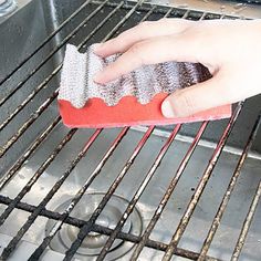 a person cleaning an oven with a sponge on the grate and in front of it