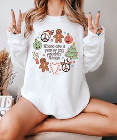 Embrace the holiday spirit with this Favorite Christmas Things Sweatshirt! Featuring adorable gingerbread men, peace signs, candy canes, and festive ornaments, this cozy sweater is perfect for all your Christmas gatherings, decorating, and cozy nights in. Soft and comfortable, this Christmas sweatshirt makes an ideal gift for her, whether she's sipping hot cocoa by the fireplace or heading out for Christmas shopping. Let this be your favorite Christmas gift for her or Christmas dinner tee this y Peace Sign Christmas, Christmas Gathering, Peace Signs, Cozy Season, Bridesmaid Shirts, Christmas Things, Gingerbread Men, Holiday Sweatshirt, Christmas Hoodies