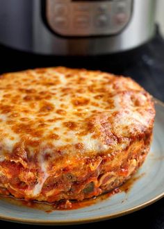 a close up of a pizza on a plate with an instant pot roast in the background