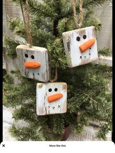 three snowmen made out of wooden blocks hanging from a tree